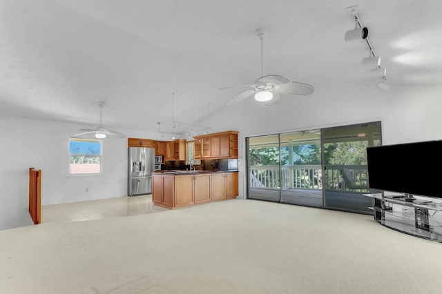 kitchen featuring stainless steel fridge, rail lighting, light colored carpet, sink, and pendant lighting