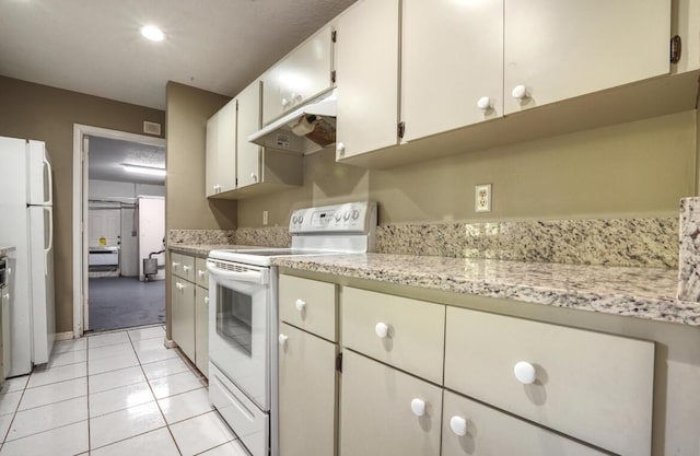 kitchen featuring white cabinets, light tile patterned flooring, light stone counters, and white appliances