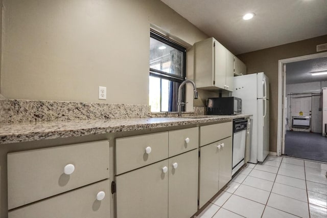 kitchen featuring light stone countertops, sink, light tile patterned floors, white appliances, and white cabinets