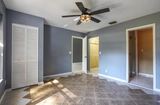 unfurnished bedroom featuring light tile patterned floors, a textured ceiling, and ceiling fan