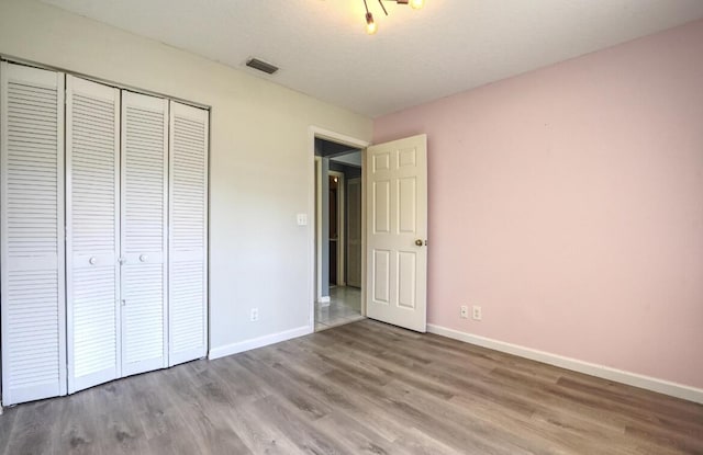 unfurnished bedroom featuring hardwood / wood-style floors, a textured ceiling, and a closet