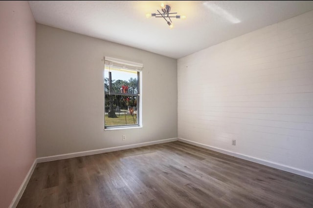 empty room featuring dark hardwood / wood-style flooring and a chandelier