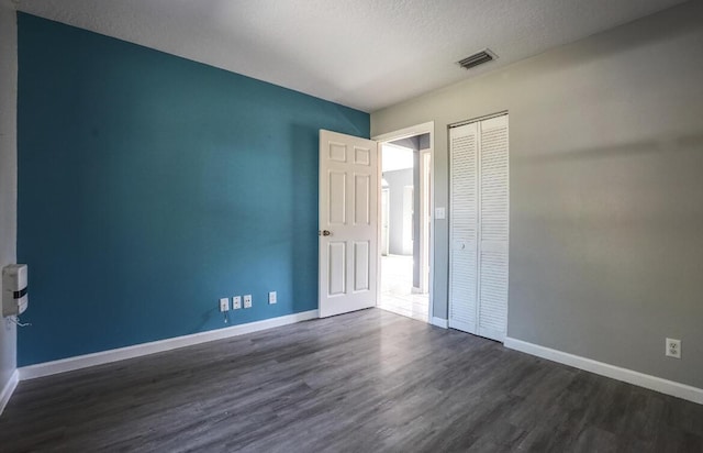 spare room featuring a textured ceiling and dark wood-type flooring