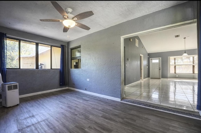 unfurnished room featuring dark hardwood / wood-style floors, vaulted ceiling, plenty of natural light, and ceiling fan