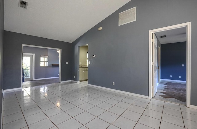 spare room with light tile patterned flooring and high vaulted ceiling