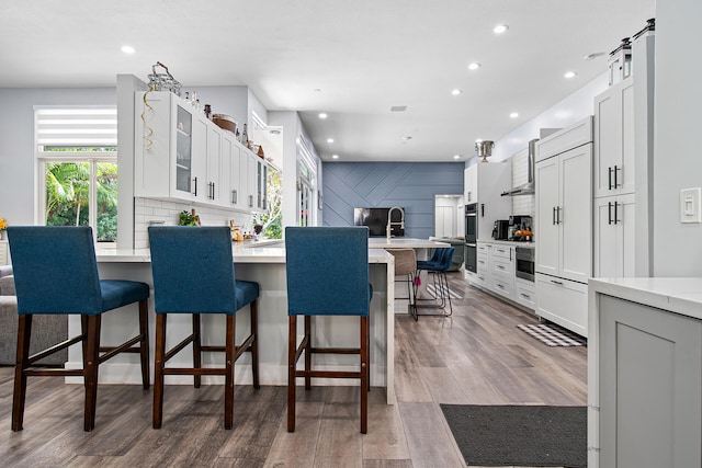 kitchen with a breakfast bar area, a barn door, white cabinetry, and light wood-type flooring