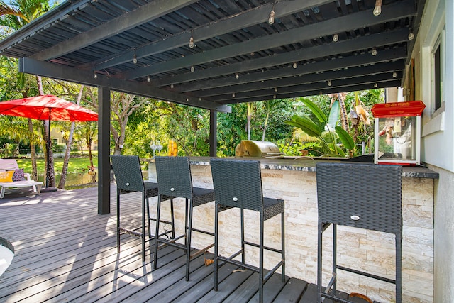 wooden terrace featuring grilling area, a bar, and exterior kitchen