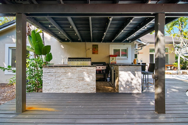 wooden terrace featuring a grill, an outdoor wet bar, and exterior kitchen