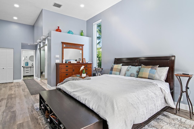 bedroom featuring ensuite bath and hardwood / wood-style floors