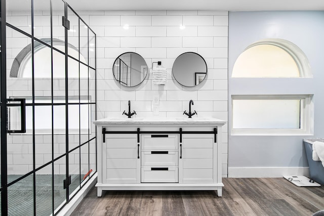 bathroom with a shower, hardwood / wood-style floors, vanity, and tasteful backsplash