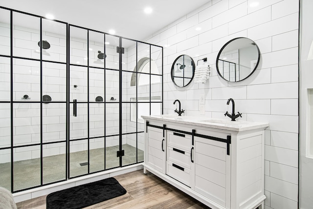 bathroom with vanity, a shower with shower door, tile walls, and hardwood / wood-style flooring