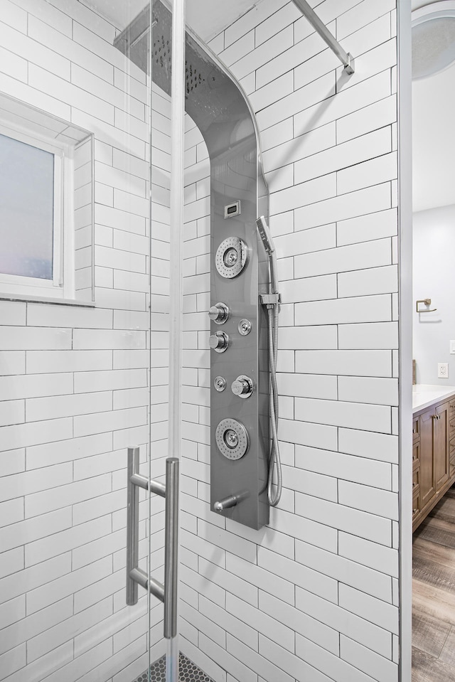 room details featuring a tile shower, vanity, and hardwood / wood-style flooring