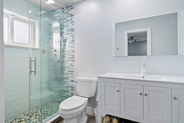 bathroom with ceiling fan, vanity, a shower with shower door, and toilet