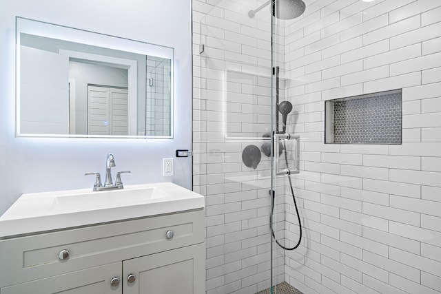 bathroom with a tile shower and vanity