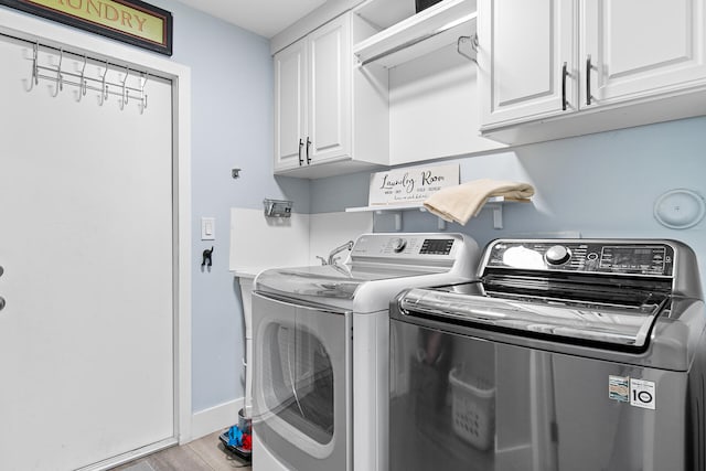 laundry room with cabinets, light wood-type flooring, and washing machine and clothes dryer