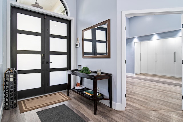 foyer with french doors, light hardwood / wood-style floors, and vaulted ceiling