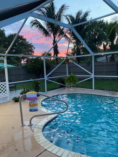 pool at dusk featuring a patio and glass enclosure