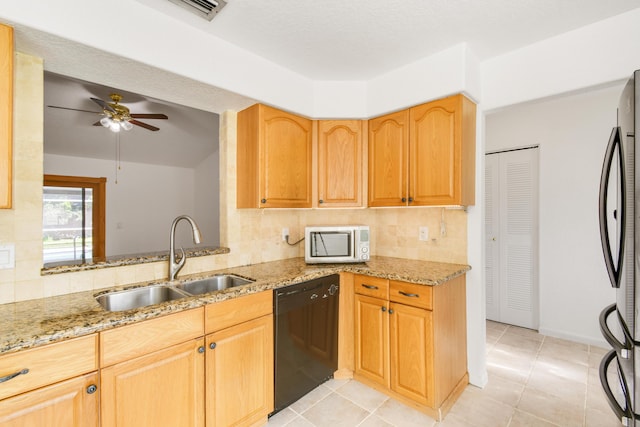 kitchen with stainless steel appliances, sink, ceiling fan, and light stone counters