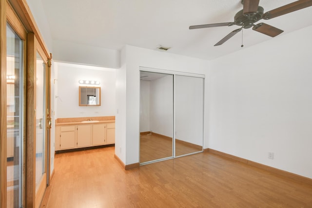 unfurnished bedroom featuring ensuite bath, ceiling fan, a closet, and light hardwood / wood-style floors