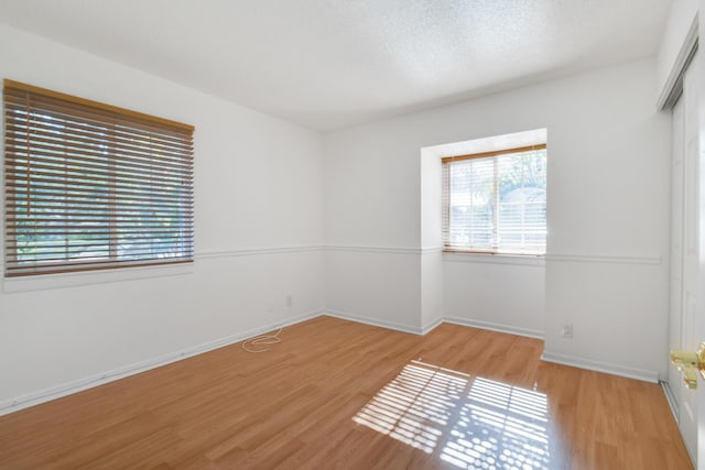 spare room with light wood-type flooring and a textured ceiling