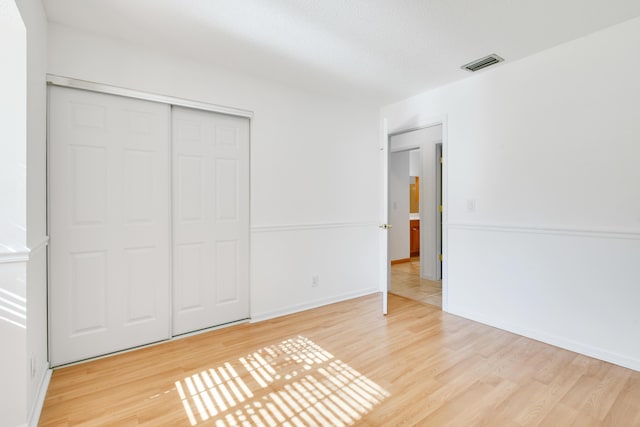 unfurnished bedroom with a textured ceiling, light hardwood / wood-style flooring, and a closet