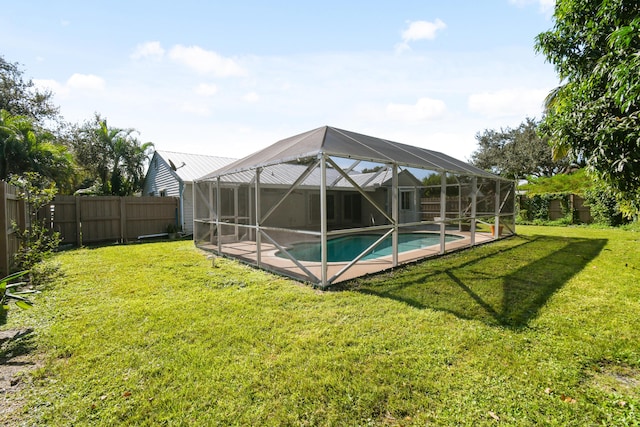 view of pool with glass enclosure and a yard