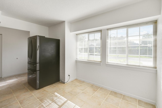 kitchen featuring stainless steel refrigerator, a textured ceiling, and light tile patterned floors