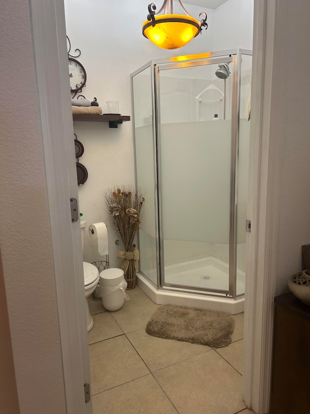 bathroom featuring tile patterned floors, toilet, and a shower with shower door