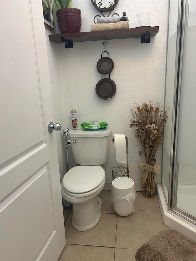 bathroom with toilet, tile patterned floors, and a shower with door