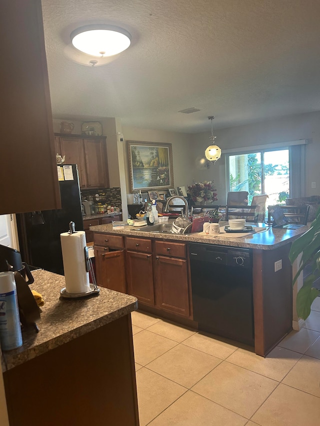 kitchen featuring refrigerator, light tile patterned floors, a textured ceiling, black dishwasher, and decorative light fixtures