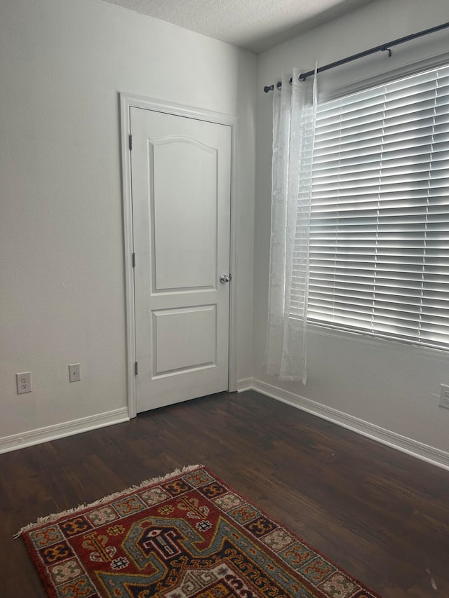 empty room featuring dark hardwood / wood-style flooring and a textured ceiling