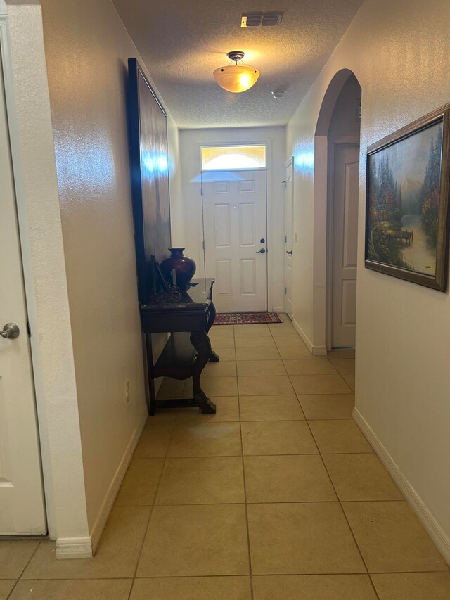 doorway to outside featuring light tile patterned floors and a textured ceiling