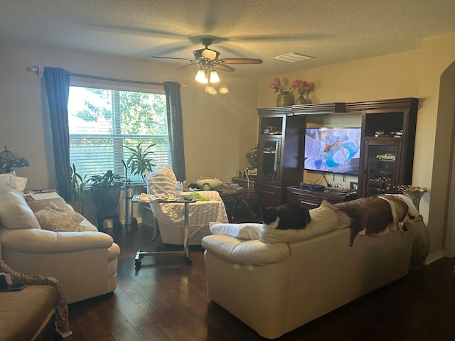 living room with a textured ceiling, dark hardwood / wood-style flooring, and ceiling fan