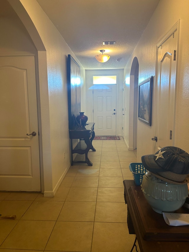 hall featuring light tile patterned flooring and a textured ceiling