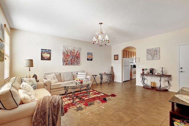 living room featuring a textured ceiling, tile patterned floors, a healthy amount of sunlight, and a notable chandelier