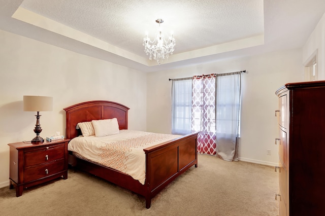 carpeted bedroom with a tray ceiling, a textured ceiling, and a notable chandelier