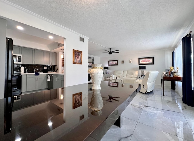 living room featuring ceiling fan, crown molding, and a textured ceiling