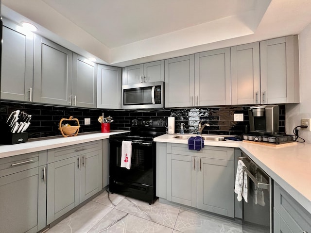 kitchen with gray cabinets, decorative backsplash, sink, and appliances with stainless steel finishes