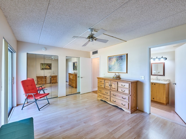 living area with ceiling fan, light hardwood / wood-style flooring, a textured ceiling, and sink