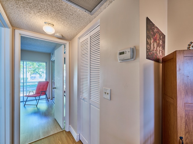 hall with light hardwood / wood-style flooring and a textured ceiling