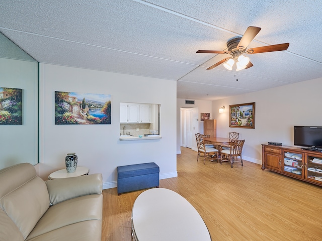 living room featuring ceiling fan, a textured ceiling, and light wood-type flooring