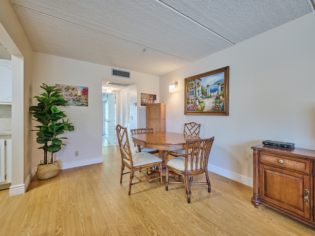 dining space with light hardwood / wood-style flooring and a textured ceiling