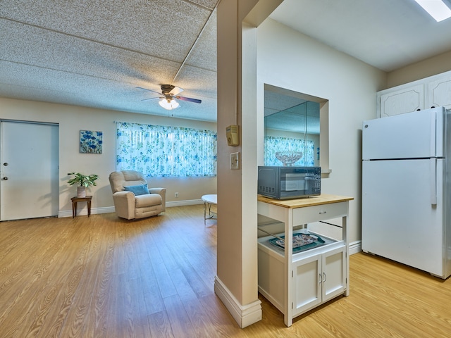 kitchen with ceiling fan, white cabinets, light wood-type flooring, and white refrigerator