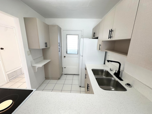 kitchen featuring light tile patterned flooring, white refrigerator, and sink