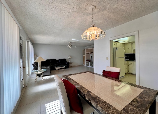 dining space with ceiling fan with notable chandelier, light tile patterned floors, and a textured ceiling