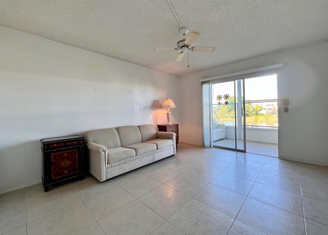 unfurnished living room featuring ceiling fan, light tile patterned floors, and a textured ceiling