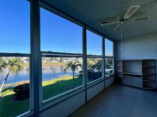 unfurnished sunroom with ceiling fan and a water view