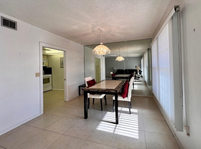 tiled dining area featuring a textured ceiling and an inviting chandelier