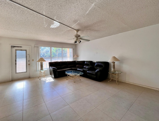 living room featuring ceiling fan, light tile patterned floors, and a textured ceiling