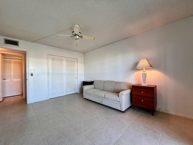 tiled living room featuring a textured ceiling and ceiling fan